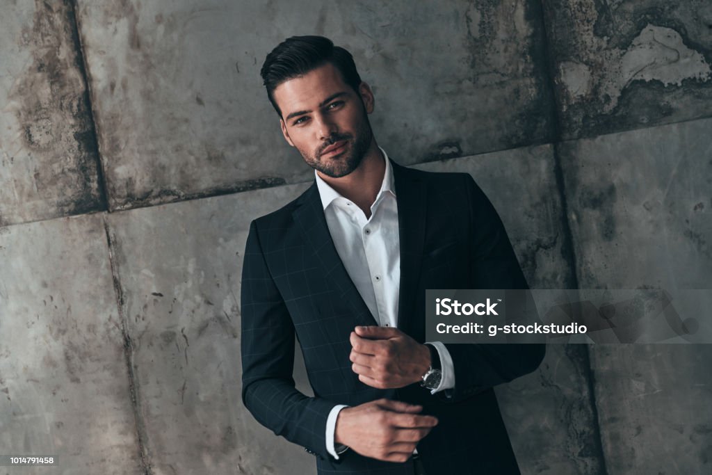 Real macho. Handsome young man in suit looking at camera and smiling while standing indoors Men Stock Photo