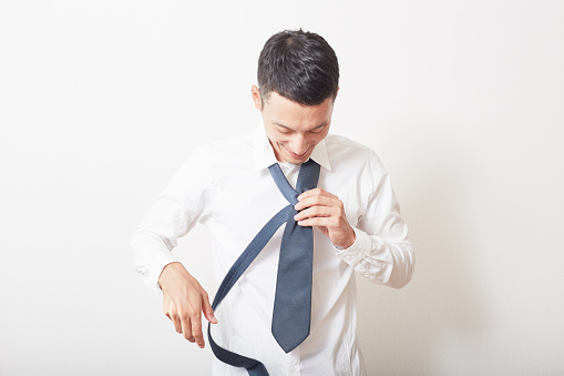 Young man suiting up, tying a tie