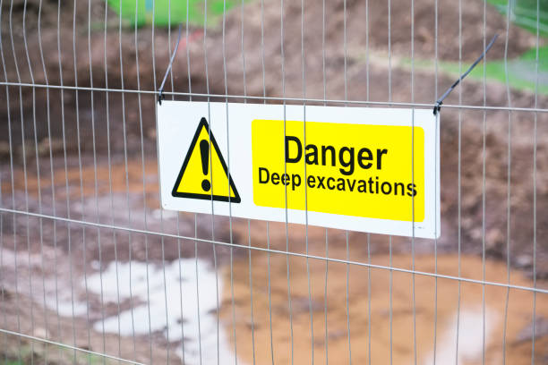 istock Deep excavations danger sign on fence with trench hole in background on construction site 1014810676