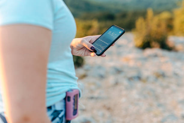 donna con diabete che indossa una pompa per insulina e controlla la glicemia su un'app per smartphone - krk foto e immagini stock