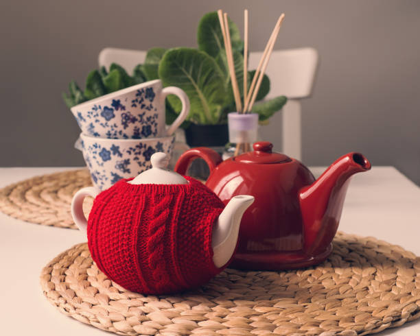 istock Lovely breakfast table with red teapot, sweater cozy teapot and teacups 1014818904
