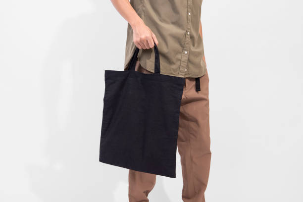 istock Man is holding black bag canvas fabric for mockup blank template isolated on gray background. 1014823910