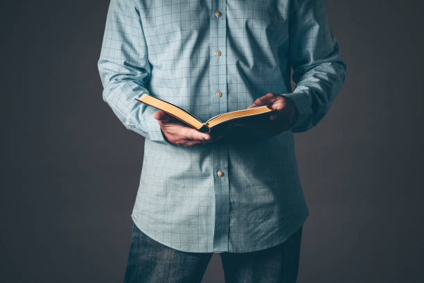 Gentleman with a bible open in his hands Gentleman with a bible open in his hands. Christian concept for faith spirituality and religion with gray background. Bible stock pictures, royalty-free photos & images