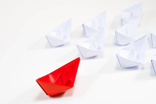 istock Beautiful red paper ship move forward among white ships on white background for leadership concept. 1014850982