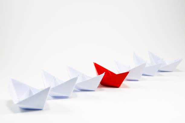 istock Red paper boat among white paper boat on white background. 1014851040