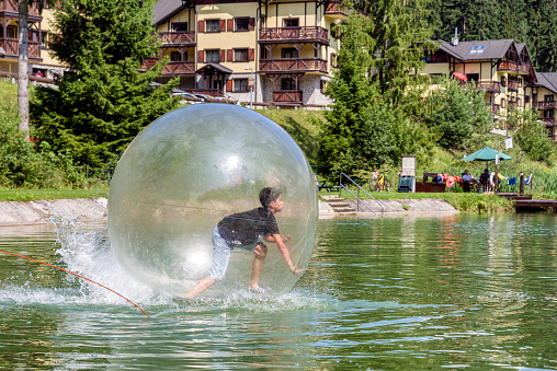 Young boy playing inside a floating water walking ball. Aquazorbing in Hrabovo, Ruzomberok