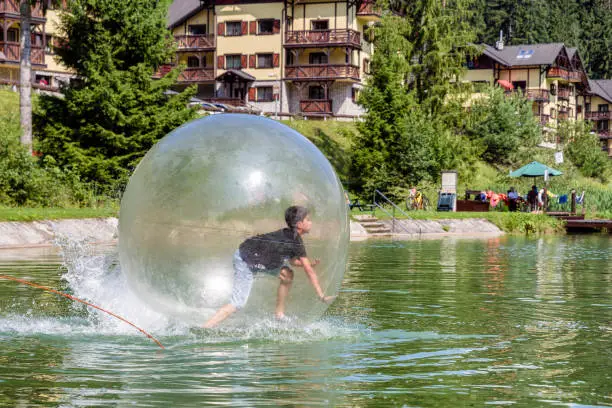 Photo of Young boy playing inside a floating water walking ball.