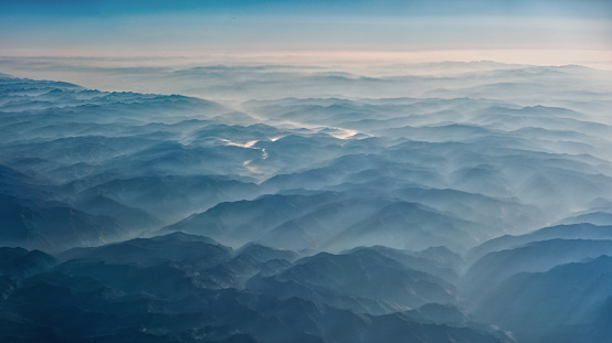 Smoke covering mountains seen from an airplane.