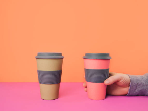 istock Hand holding take away coffee cup on colorful paper background. Recycling consept. 1014857480