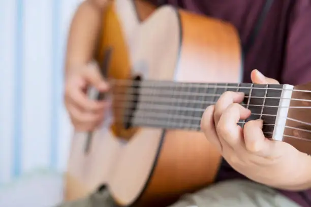 Close up of unknown little boy hands practicing to strumming an acoustic guitar