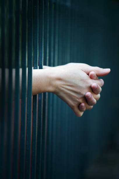 istock close up of hands in jail background. 1014879356