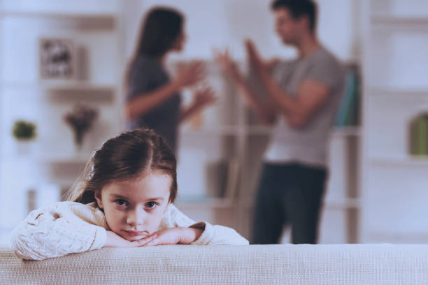 istock Sad Little Girl with Quarrel Parents. 1014887952