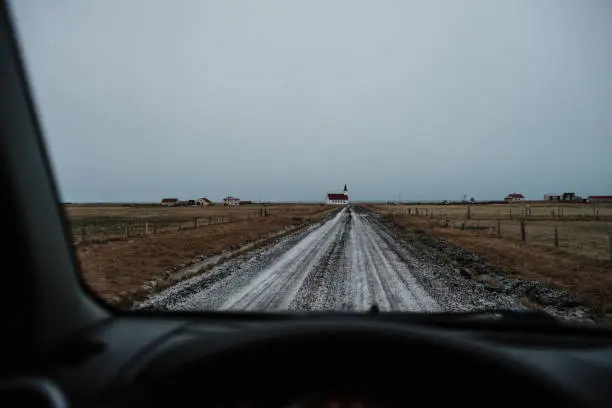 The view from the front window of a car onto a straight dirt road in Iceland