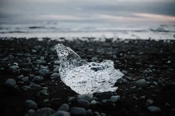 Some ice crystals lying on a black beach in front of the ocean on Diamond Beach in Iceland