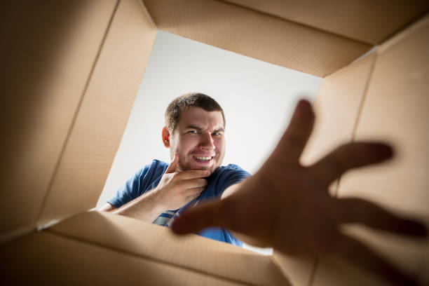 istock Man unpacking and opening carton box and looking inside 1014891206
