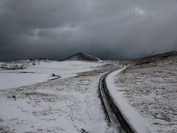 A curvy road in Iceland going through a snowy landscape, shot with a drone
