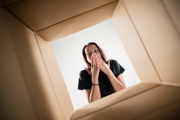 Woman unpacking and opening carton box and looking inside