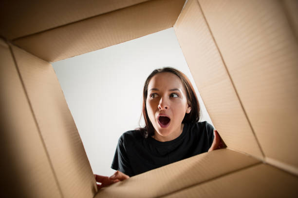 istock Woman unpacking and opening carton box and looking inside 1014900554