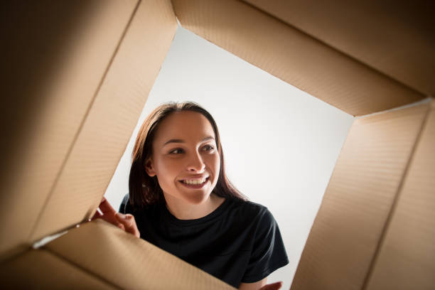 istock Woman unpacking and opening carton box and looking inside 1014900576