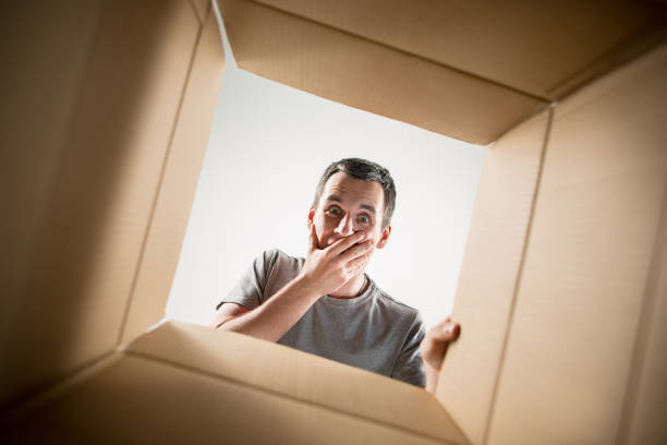 istock Man unpacking and opening carton box and looking inside 1014903178