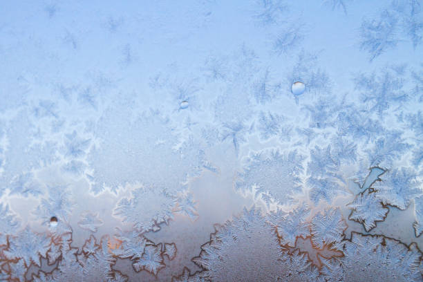 istock Winter frosty patterns on the frozen ice window 1014915968