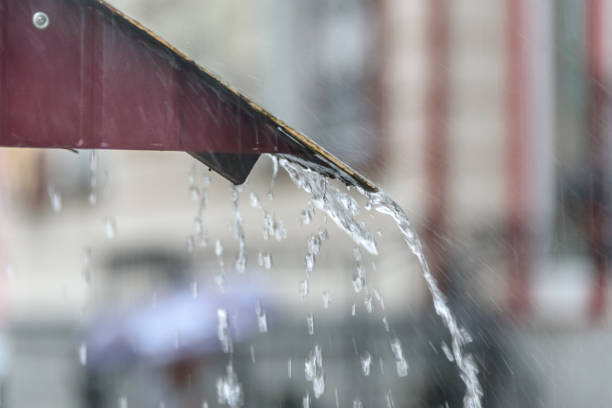 istock Storm rain drips down from the roof with a powerful stream 1014921154