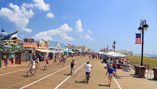 Ocean City boardwalk in New Jersey, USA Ocean City, New Jersey - August 05, 2018:  People walking and biking along the boardwalk in Ocean City, New Jersey, USA boardwalk stock pictures, royalty-free photos & images