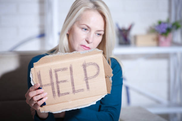 istock Woman alcoholic social problems concept sitting asking for help. Middle aged woman holding a sign m asking for help. Copy paste 1014924716