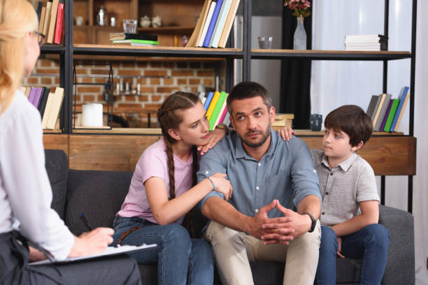 istock children cheering up father while he talking to female counselor on therapy session 1014934132