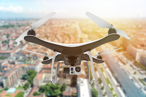 Drone with digital camera flying over a city at sunset: 3d illustration