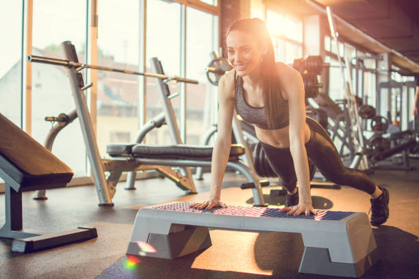 young woman doing push-ups on exercise stepper in the gym - the next step imagens e fotografias de stock