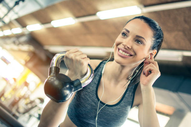 ritratto di bello sorridente con auricolari che sollevano pesi in palestra - picking up weight women sport foto e immagini stock