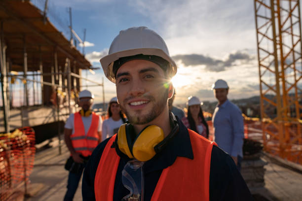 portrait of a happy construction worker at a building site - capacete imagens e fotografias de stock