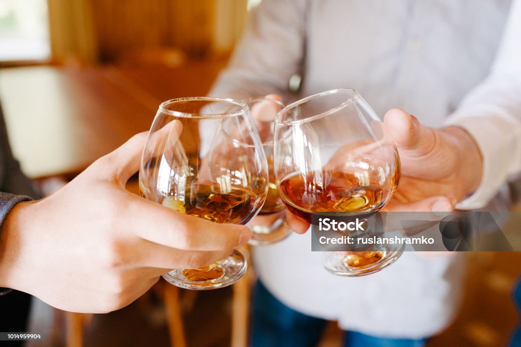 Groupe d’amis un toast sous les acclamations de cognac ou de brandy - Photo de Eau-de-vie de vin libre de droits