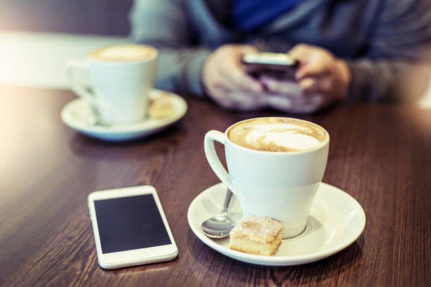 istock Two cappuccinos and background man using mobile phone 1014962084
