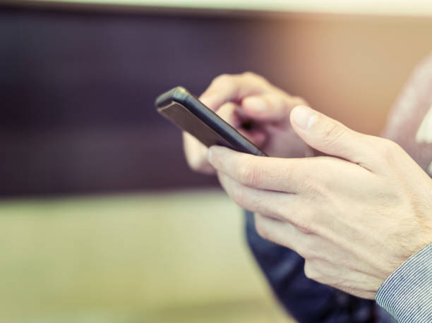 istock Male hands holding mobile phone and texting with defocused background 1014962086