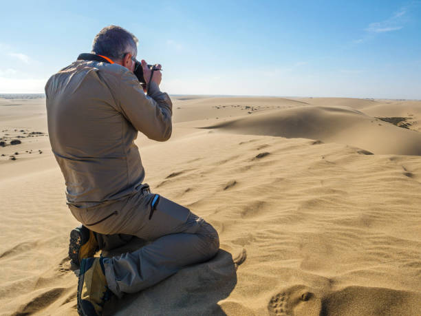 Man taking pictures on desert Photographer taking some pictures of the dunes over the sand on the Namib desert, Namibia tecnología inalámbrica stock pictures, royalty-free photos & images