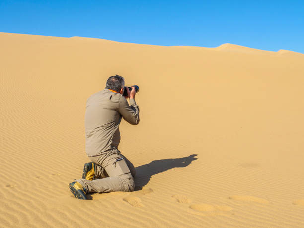 Man taking pictures on desert Photographer taking some pictures of the dunes over the sand in Namib desert tecnología inalámbrica stock pictures, royalty-free photos & images