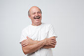 Mature adult man with moustache laughing looking at the camera over white background.