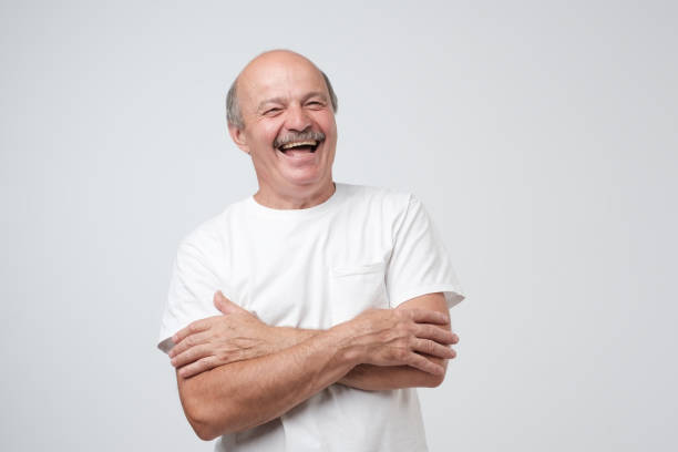 Mature adult man with moustache laughing looking at the camera over white background. stock photo