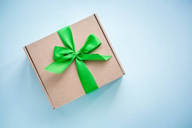 istock Craft paper box with green ribbon bow on blue 1014980362