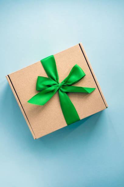 istock Craft paper box with green ribbon bow on blue 1014980406