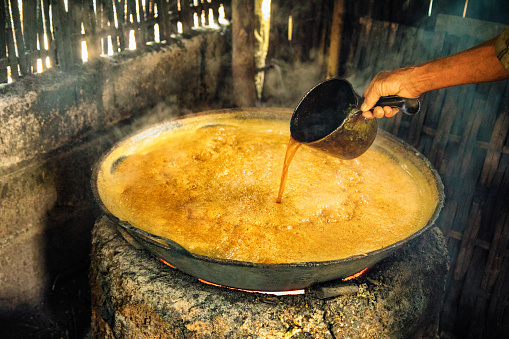 Pouring Palm sap in large burning pot in a small Balinese kitchen.