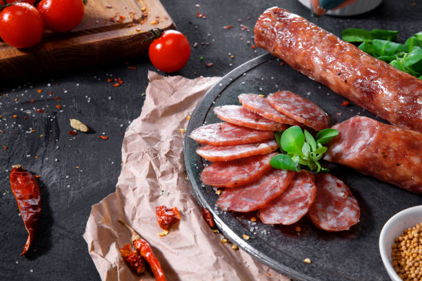 istock Sliced sausage on the board on dark background. 1014986894