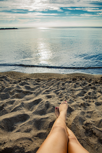 A woman's legs relaxing in the sands of Lake Erie, in Presque Isle, Erie, Pennsylvania.