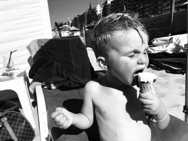 little boy in a beach club with an ice cream black and white art