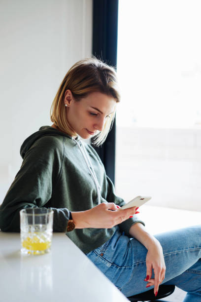 istock A model look blonde caucasian female is reading emails on her mobile phone while sitting in a modern coworking space. A fashion blogger female is typing message on her smartphone. 1015016296