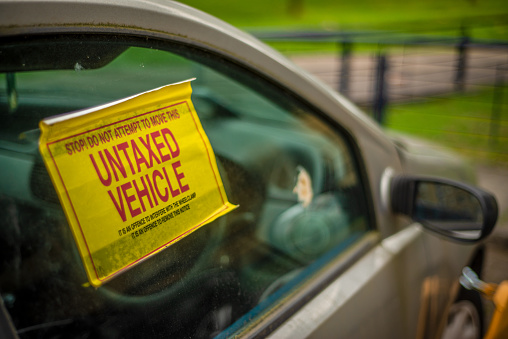 Detail Of A Warning Sign On The Window Of An Untaxed Vehicle WIth A Clamp On The Front Wheel
