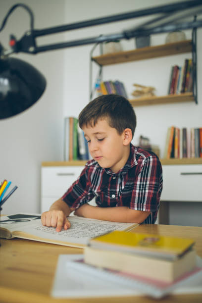 Boy studying for school at home Boy studying for an exam for school at his desk at home report card stock pictures, royalty-free photos & images