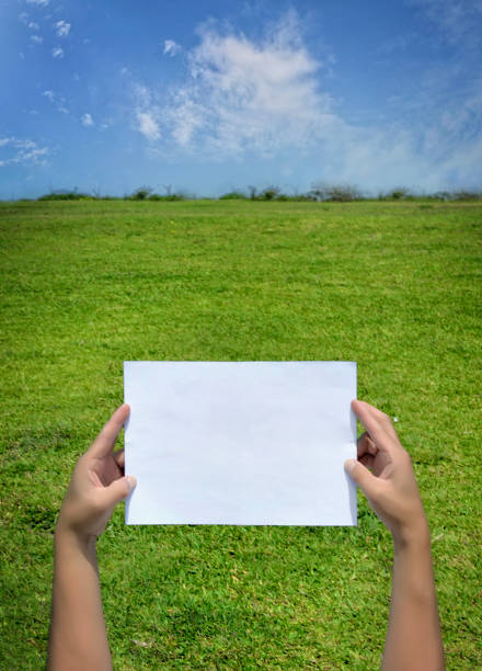 istock Young man's hand holding blank paper. Blue sky. 1015022566